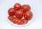 Red tomatoes on a white plate. Sliced tomatoes on a white background. Vegetables on a plate