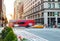 Red tour bus and yellow taxi driving through the busy intersection of 23rd Street and 5th Avenue in Manhattan, New York City