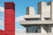 Red tower made of wood beside a concrete building with concrete towers and blue sky with white clouds