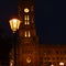 The Red Town Hall in the center of Berlin at night. In the foreground is a historic Berlin lantern on which the focus lies.