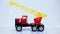 Red toy crane truck with hook model car rotating on white background.