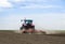 Red tractor driven by farmer cultivating land