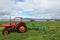 Red tractor in a field in front of a lake, Iceland.