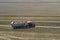 A red tractor harvests ripe golden wheat on a grain field harvested by harvesters. Agricultural work in summer.