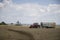 A red tractor harvests ripe golden wheat on a grain field harvested by harvesters. Agricultural work in summer.