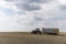 A red tractor harvests ripe golden wheat on a grain field harvested by harvesters. Agricultural work in summer.