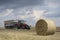 A red tractor harvests ripe golden wheat on a grain field harvested by harvesters. Agricultural work in summer.