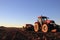 Red tractor in open field with planter