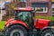 Red tractor parked in a residential area, countryside transportation background, peasant visiting a village