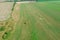 A red tractor rakes the mown grass in the drying field. Top view of modern farmer machinery.