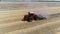 A red tractor with a reverse plow plows a field.