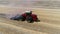 A red tractor with a reverse plow plows a field.