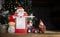 red tractor, souvenir figurines of snowman, Santa Claus, festive notebook against of garland lights
