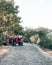 A red tractor stands by the road in the countryside. A man with a foot stands near a tractor