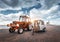 Red tractor with trailer against lighthouse and cloudy sky