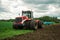 Red tractor working in a field on a bright sunny day. The concept of work in a fields and agriculture industry