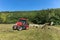 Red tractor working in a field with a two-rotor tedder. Drying hay in the meadow. Work on an agricultural farm