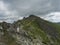 Red trail post sign at steep hiking path on ridge of rohace mountain to peak ostry rohac. Sharp green rocks, Summer blue