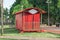 Red trailer through the park with old railway track, some benches and many trees and green nature around. Plate to put your