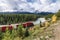 Red train long freight on railway passing in autumn valley and bow river at Morant\'s Curve