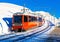 Red train running on rack railway through snowy Swiss Alps