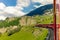 Red train slowly climbing to the Bernina Pass in the Swiss Alps