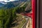 Red train slowly climbing to the Bernina Pass in the Swiss Alps