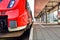 A red train is waiting at an empty platform for departure