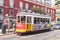 Red tram rides down the street of Lisbon