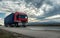 Red transportation semi trailer truck on a highway at sunset