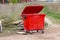 Red trash bin with ajar lid. Garbage around the container. The photo