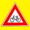 A red triangle beware of cyclists warning sign on a yellow background