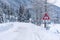 Red triangle road traffic warning sign - Other Danger. Crossroads with cross-country skis paths . Snow covered road, trees