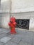 Red triple fire hydrant on the street near the window with a pattern in the French city of Reims