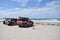 Red trucks parked by orange cones on sandy beach