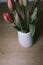 Red tulip flower bouquet blossoming on a white pot over a blurry wooden table