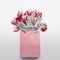 Red tulips bouquet in paper shopping bag on light gray background. Festive spring flowers bunch. Floral gift composing.
