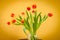 Red tulips in a glass vase on mosaic table.