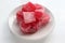 Red Turkish delights with sugar powder on plate on white table background. Oriental dessert sweet candy rahat locum.
