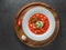 Red ukrainian borscht in white plate on wooden plate with red pepper and garlic