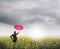 Red umbrella Business woman standing in rain clouds over sunflowers field