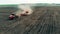 Red vehicle makes furrows for seeds on a farmland, top view.