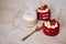 Red velvet cakes, portioned, decorated with cherries and strawberries. transparent mug of cappuccino with a cinnamon stick. delici