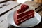 Red velvet cheese cake in a white dish on wood table in a garden style coffee shop