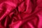 Red velvet fabric wavy folds for background texture. Fragment of a soft wrinkled dark red cloth material