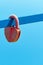 Red velvet padlock in the shape of a heart on a cyan railing on a blue sky background