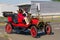 A red vintage 1912 Ford T is driving down a city street.