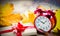 Red vintage alarm clock and gift box with maple leaves