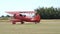 Red vintage biplane from the 1930s parked in a grass airfield in the countryside