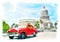 Red vintage car passing by the Capitolio in Havana